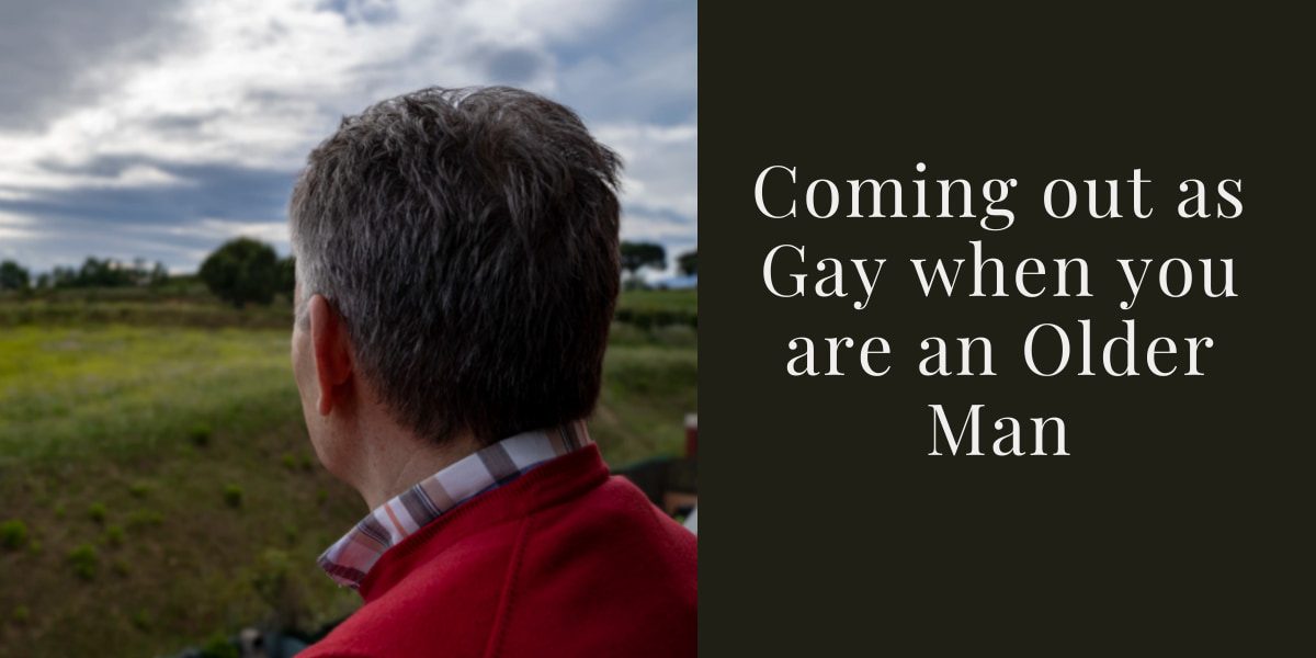 A man with grey short hair looks towards a green field with grass and trees with his back to the camera. We see him from the top of the shoulders up. The collar of a checked shirt appear from a red jumper. The caption reads &quot;Coming out as Gay when you are an Older Man&quot;