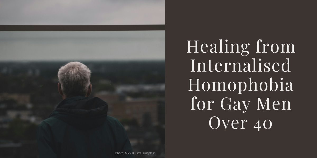 Older man with grey hair seen from behind, looking out over a cityscape on a cloudy day. Beside him is text that reads: &#39;Healing from Internalised Homophobia for Gay Men Over 40&#39;.