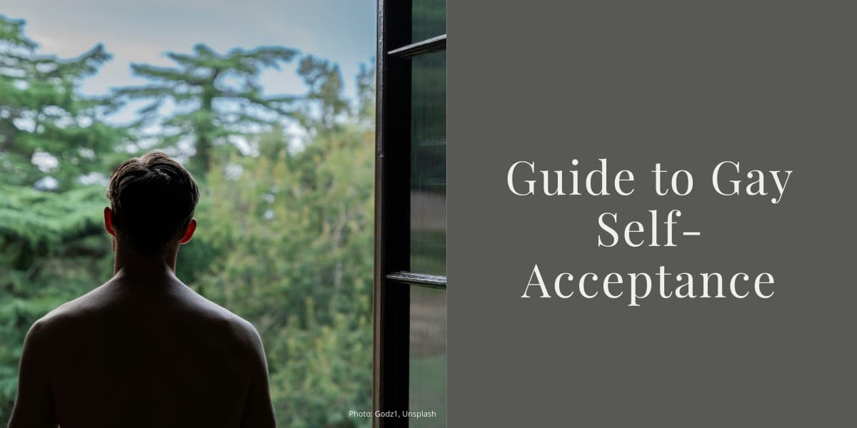 The back of a shirtless man looking out of a window onto a park or woodland.