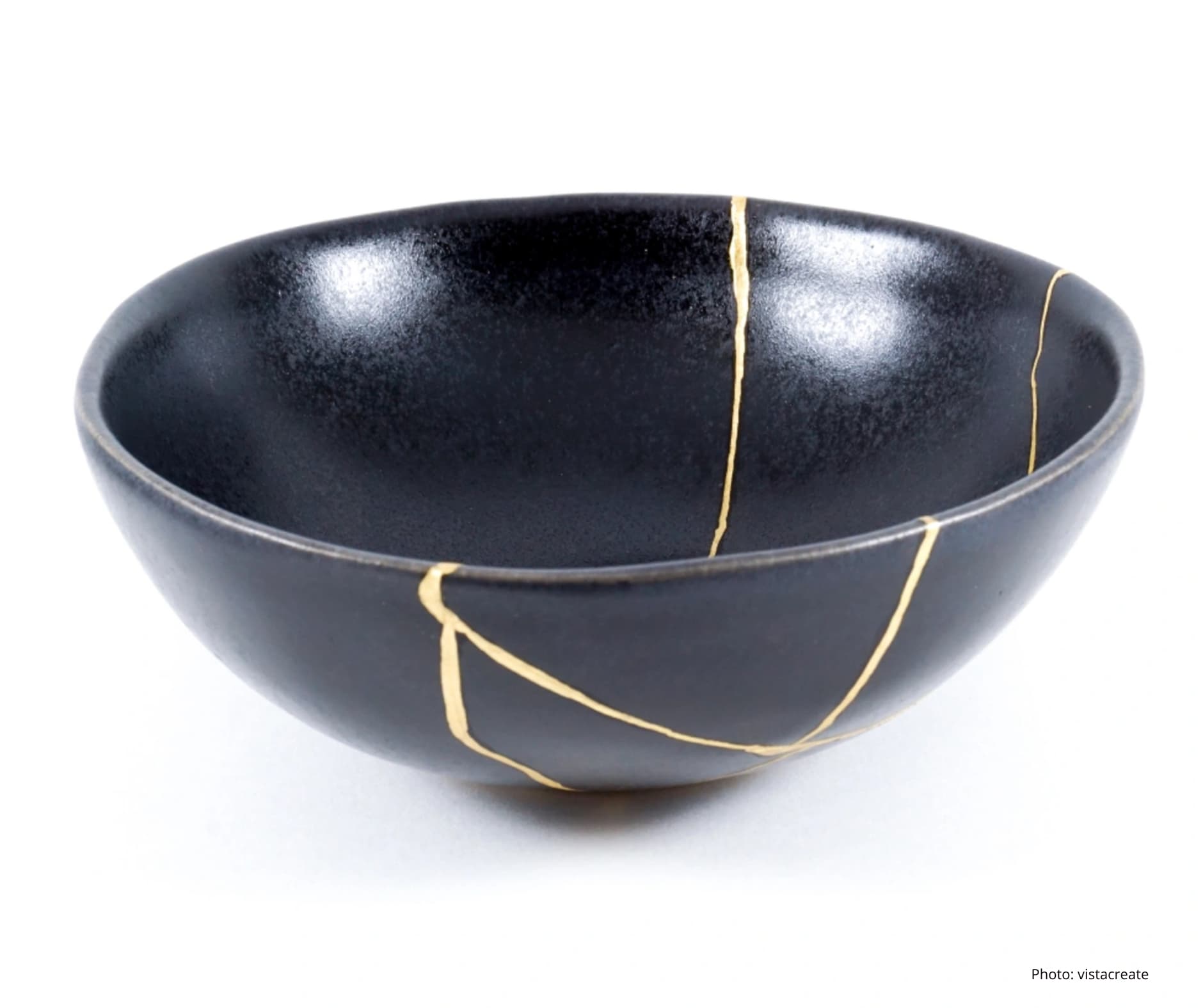A beautifully repaired ceramic bowl, following the Japanese art of Kintsugi. Cracks are filled with shining gold lacquer, highlighting the breaks as a beautiful part of the object's history.